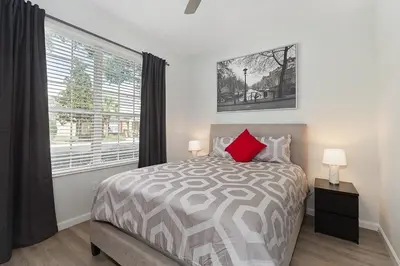 a bedroom with a bed with a red pillow and a window at Charming 3BR Townhome Private Pool Walk to Clubhouse 9 Min Disney in Orlando