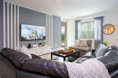 a living room with a leather couch and a tv at Exclusive 8BR Family Villa - Pool, BBQ, Game Room & Themed Bedrooms! in Kissimmee