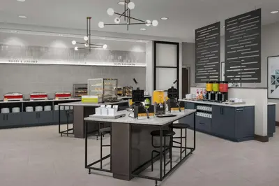 a kitchen with counters and tables in a room at Home2 Suites Orlando Southeast Nona in Orlando