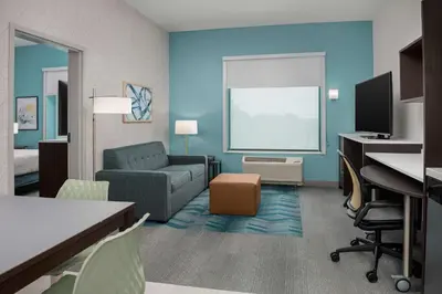 a living room with a couch and a desk at Home2 Suites Orlando Southeast Nona in Orlando