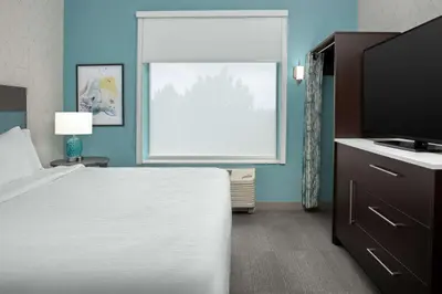 a bedroom with a bed and a large window at Home2 Suites Orlando Southeast Nona in Orlando