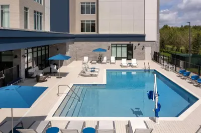 a large swimming pool with chairs and umbrellas at Hampton Inn Orlando Southeast Nona in Orlando