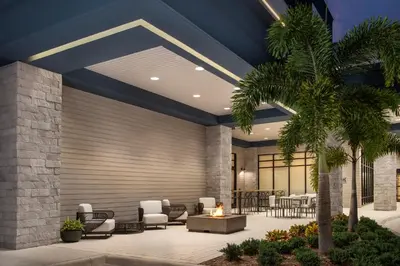 a lobby with chairs and tables and a palm tree at Hampton Inn Orlando Southeast Nona in Orlando